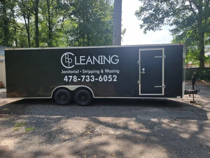 A fourty foot long black and chrome pulled style trailer with the BP Cleaning logo on the side, parked in front of a residential building.